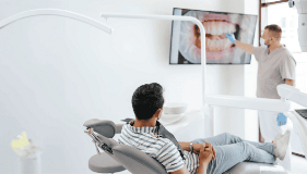 Orthodontists pointing at chart with patient looking from chair